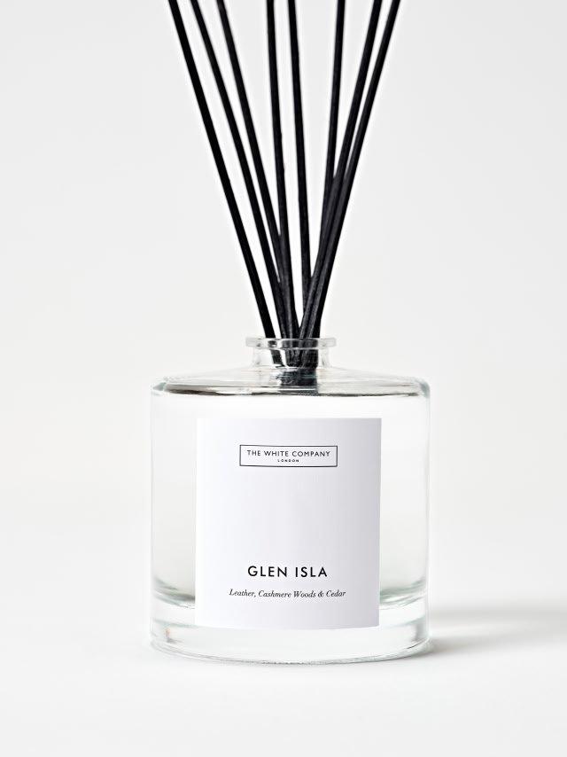 a glass bottle with reed diffusers in it on a table