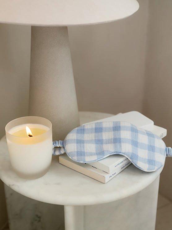 a white table with a blue and white eye mask and a candle