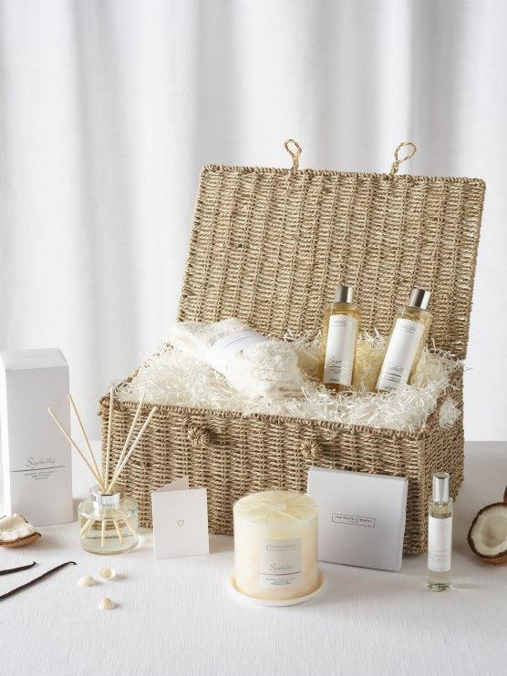 a wicker basket filled with various items including candles, lotions and soaps