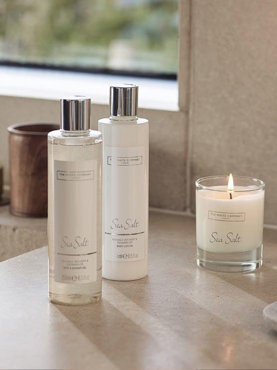 a couple of bottles of lotion and a candle sit on a counter