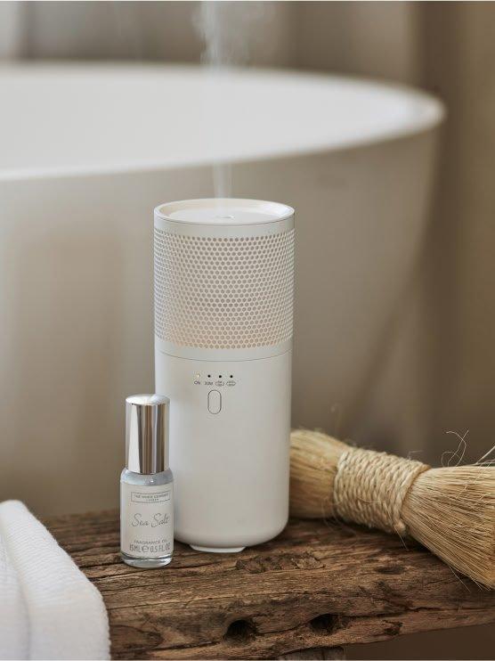 a white and blue bottle of essential oil sitting next to a white tub