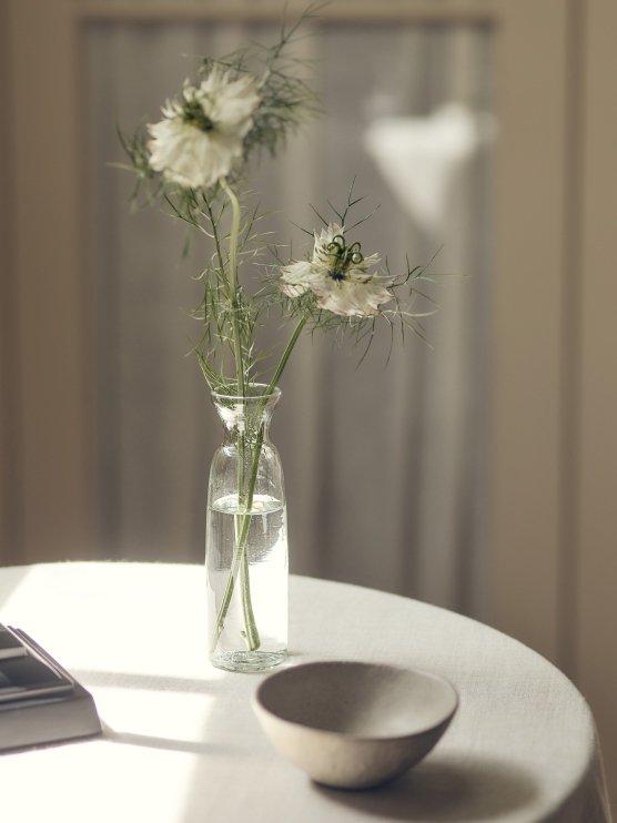 a vase with flowers on a table with a yellow bowl