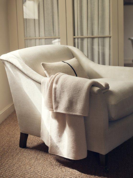 a white chair with a blanket on it in a room