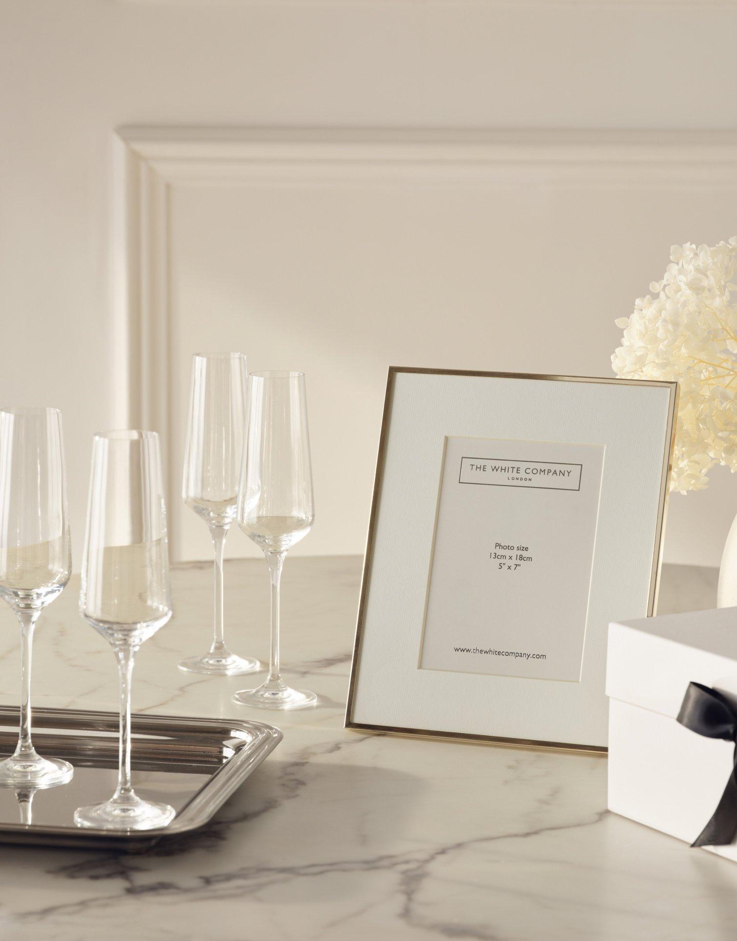 a table with a picture frame and wine glasses on it