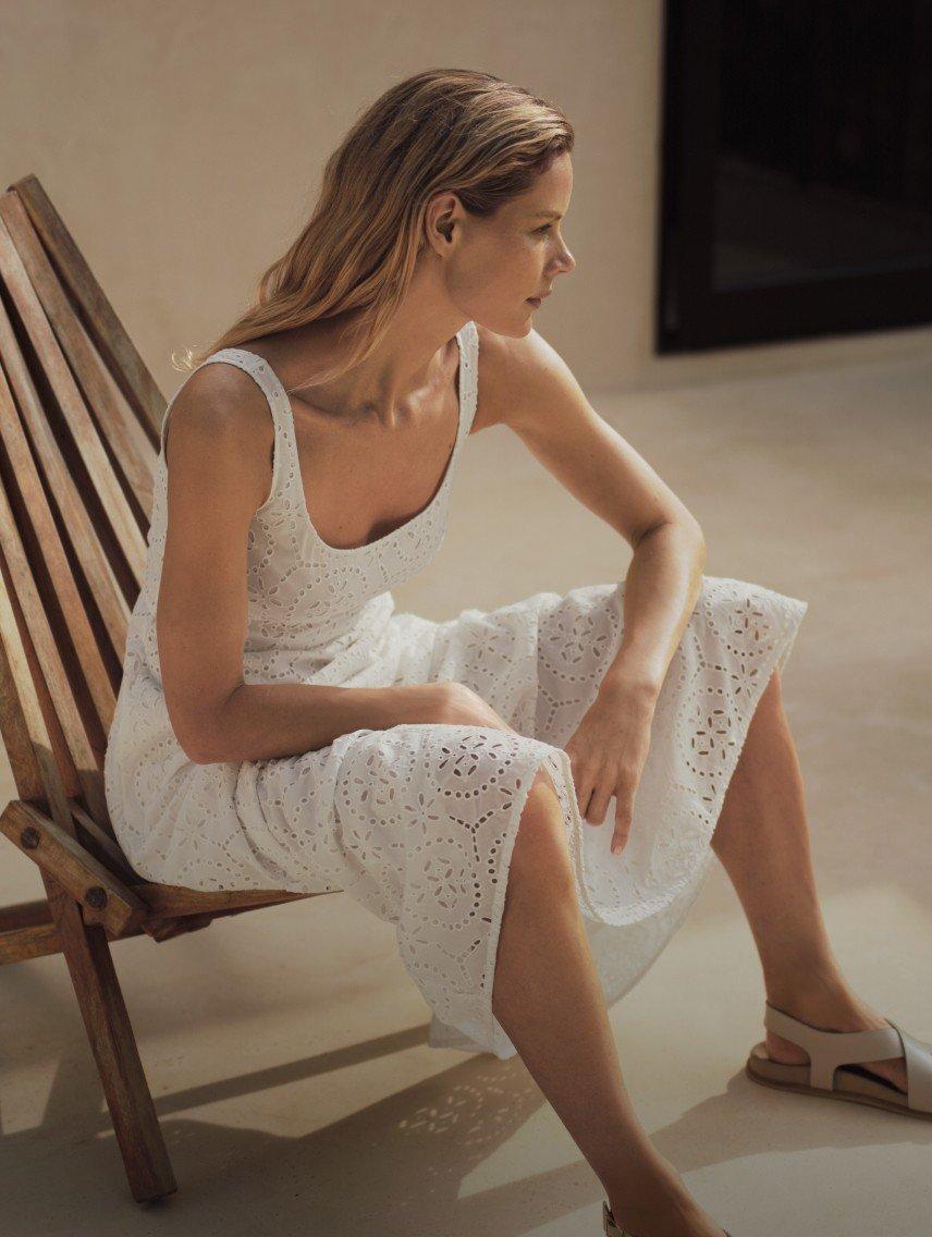 a woman sitting on a chair in a white dress