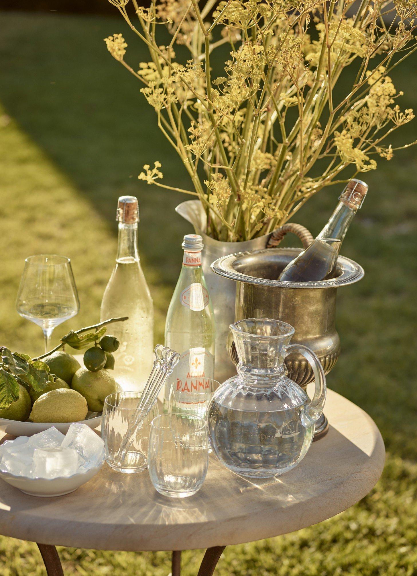 a table with a vase of flowers and bottles of wine
