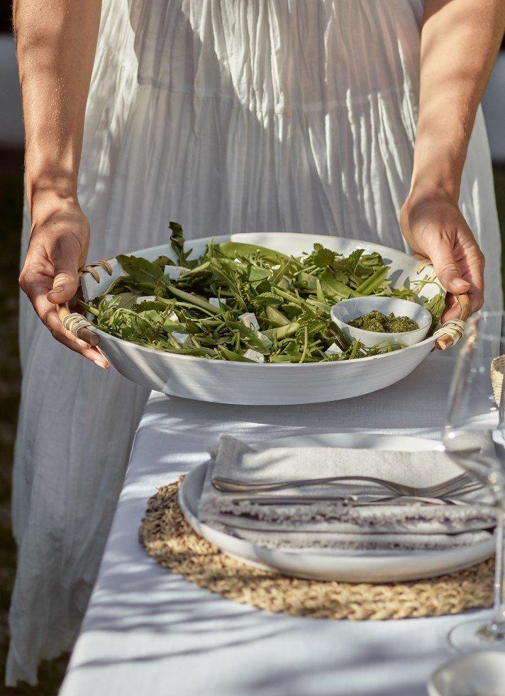 a woman holding a bowl of salad on a table