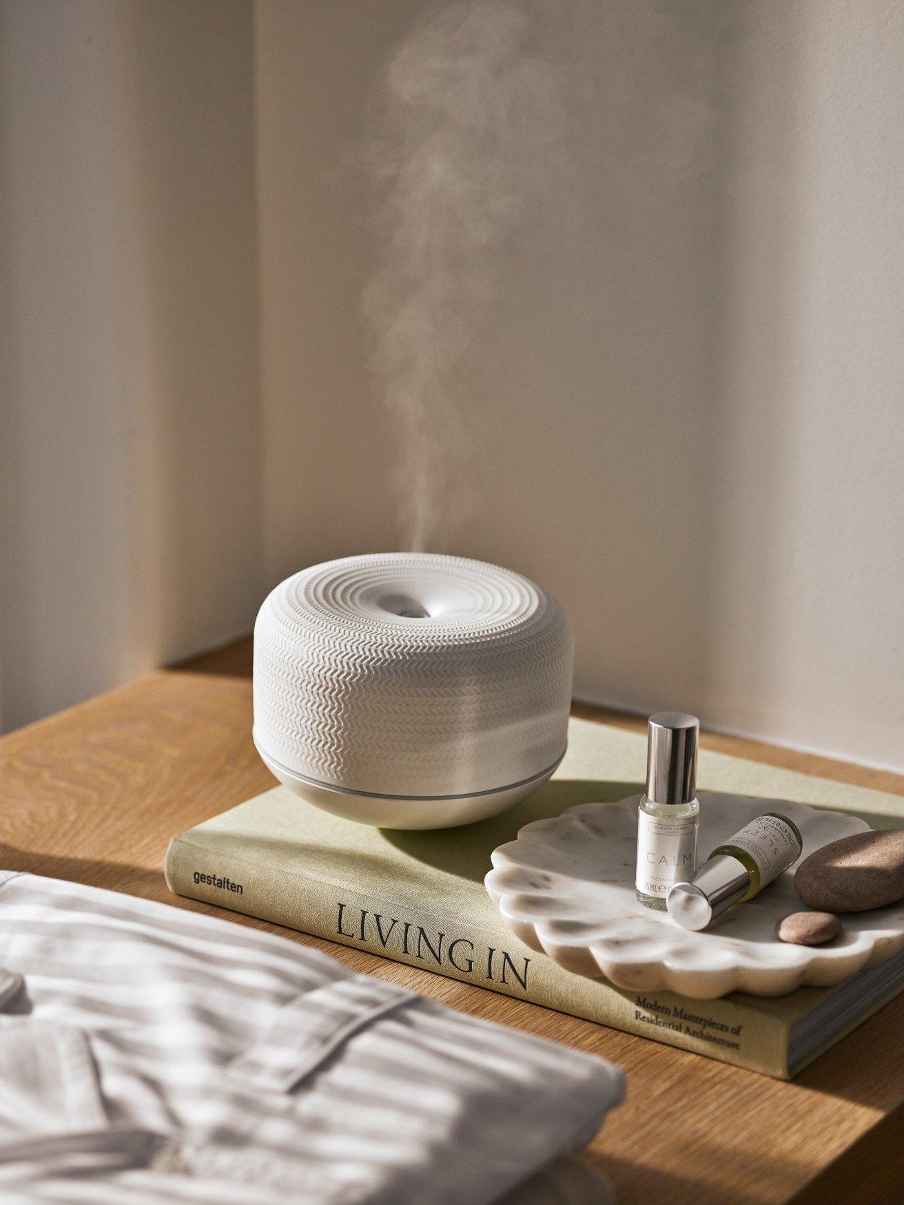 a table with a book, a bottle of water and a diffuser