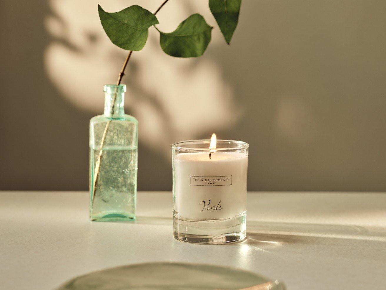 a candle and a vase on a table with a leaf