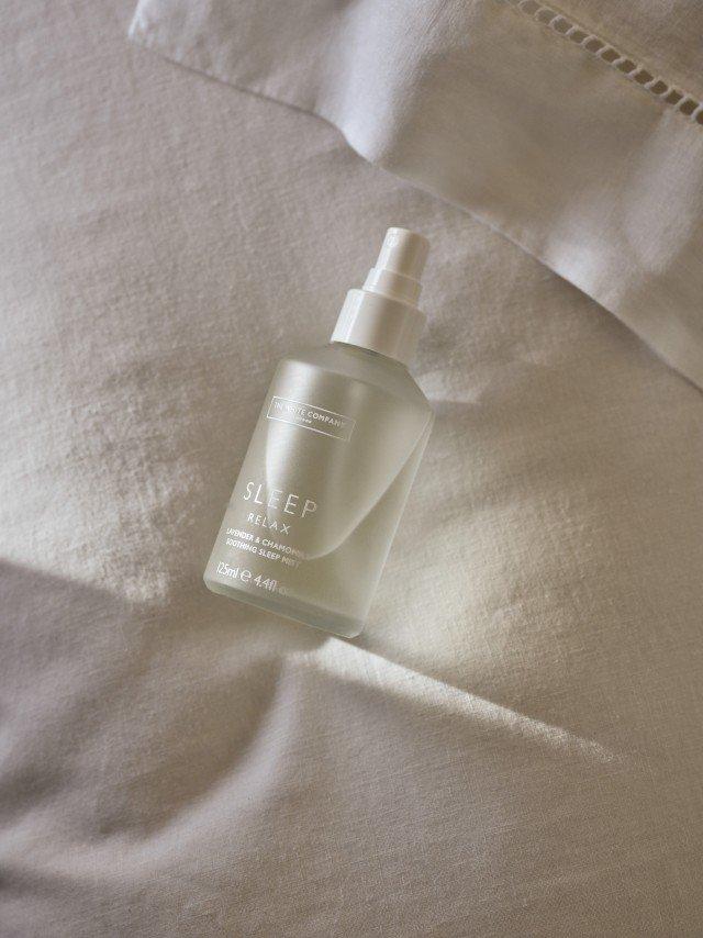 a bottle of a sleeping spray sitting on top of a bed