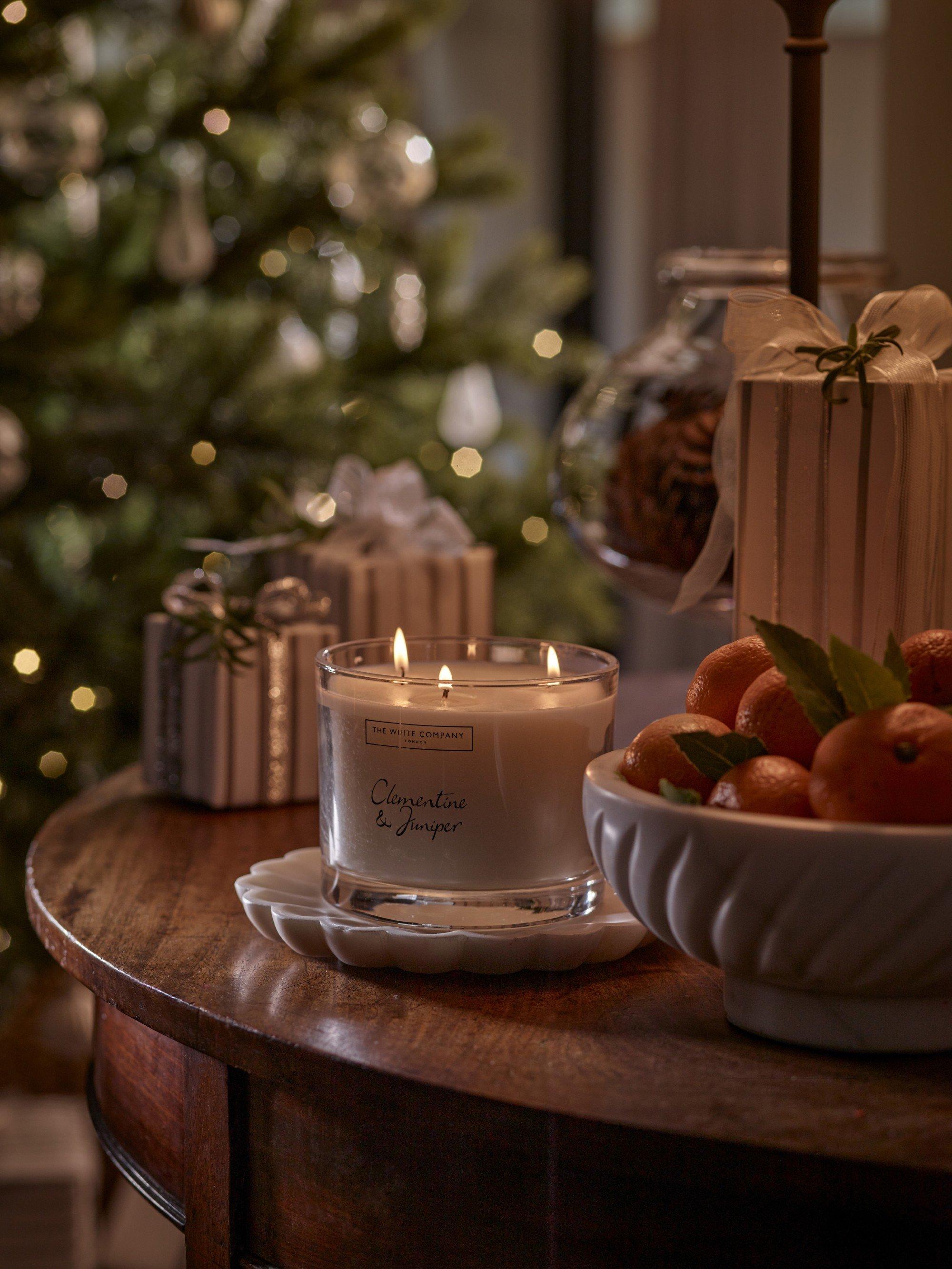 a candle and some wood chips on a table next to a plant