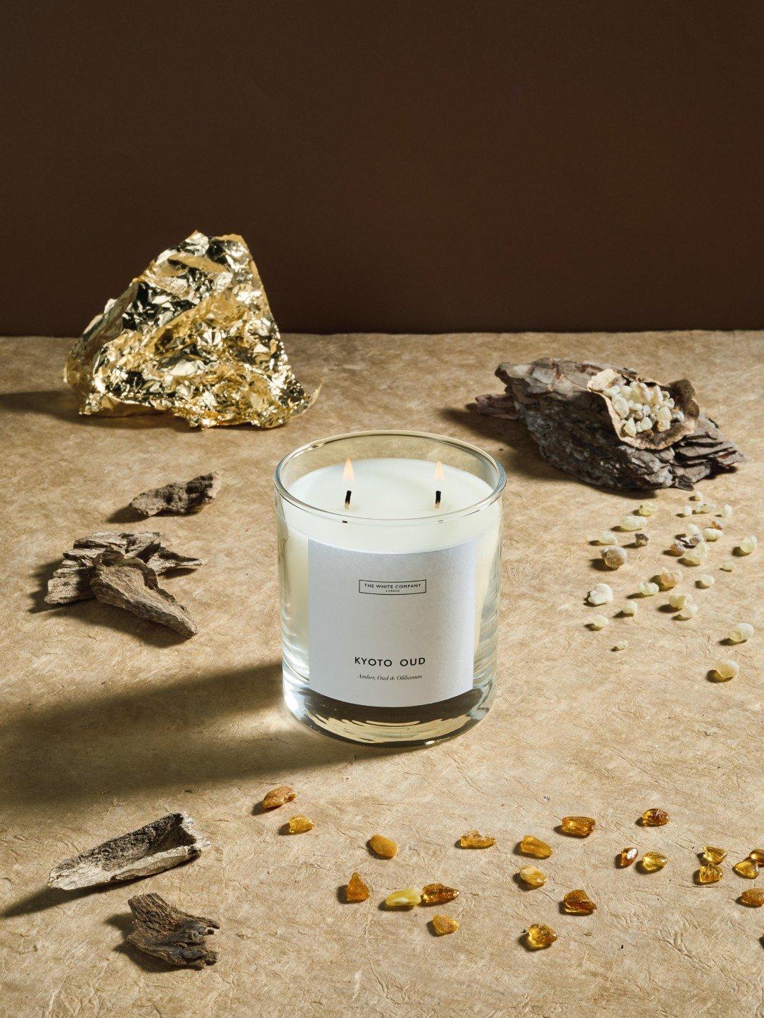 a candle and some wood chips on a table next to a plant