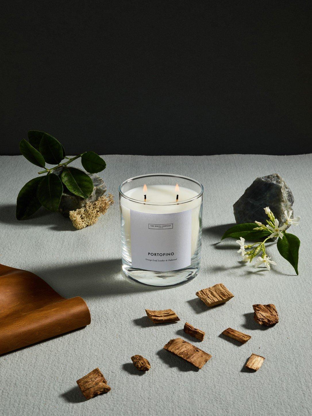 a candle and some wood chips on a table next to a plant