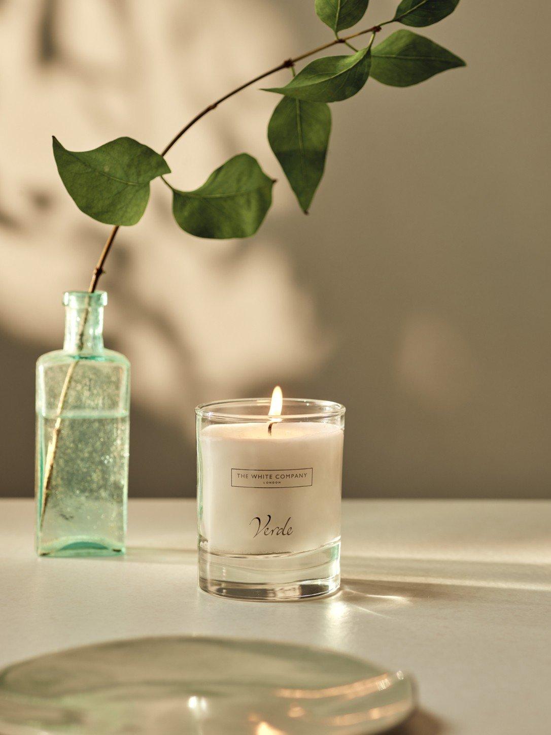 a candle and a vase on a table with a leaf