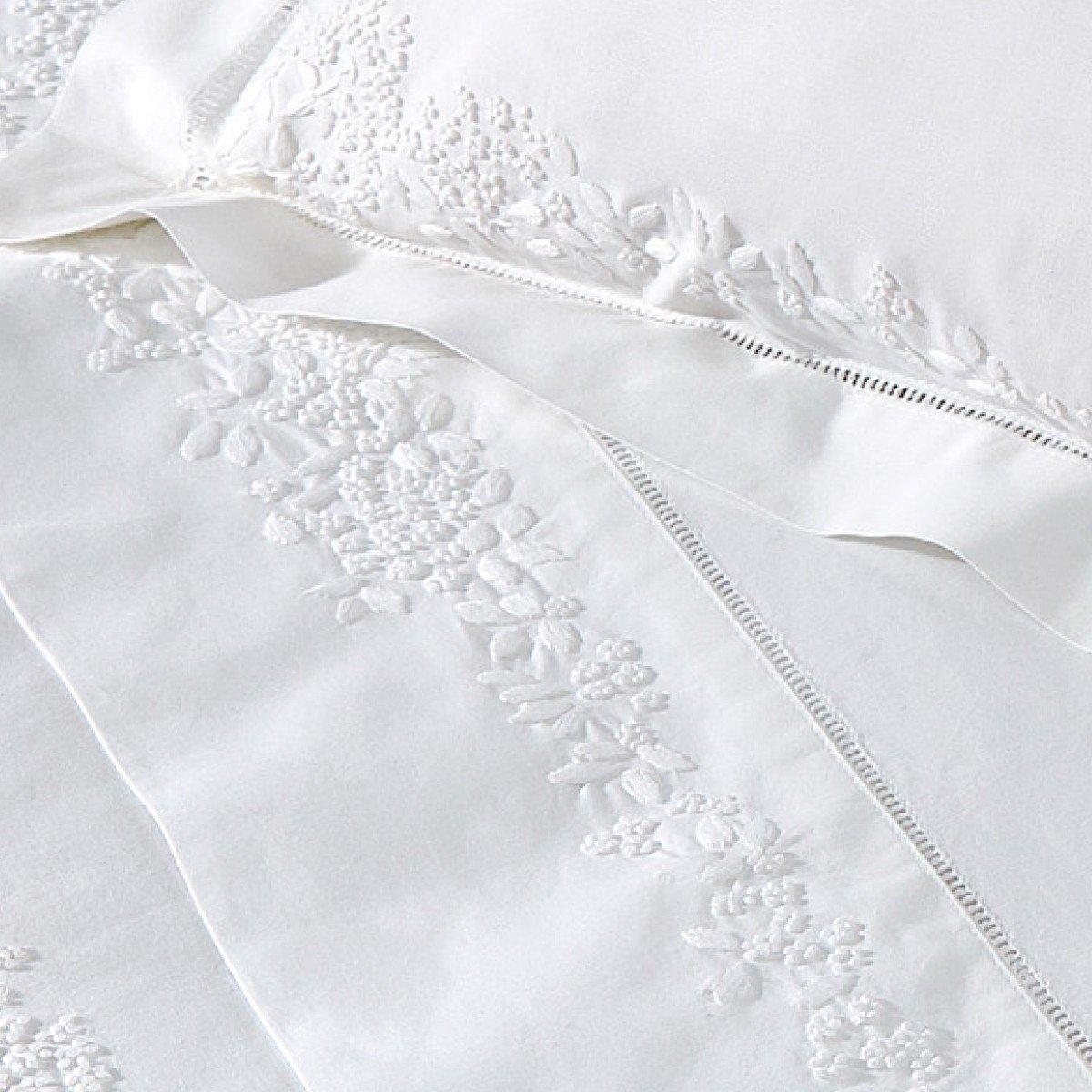 a close up of a bed with white sheets and pillows