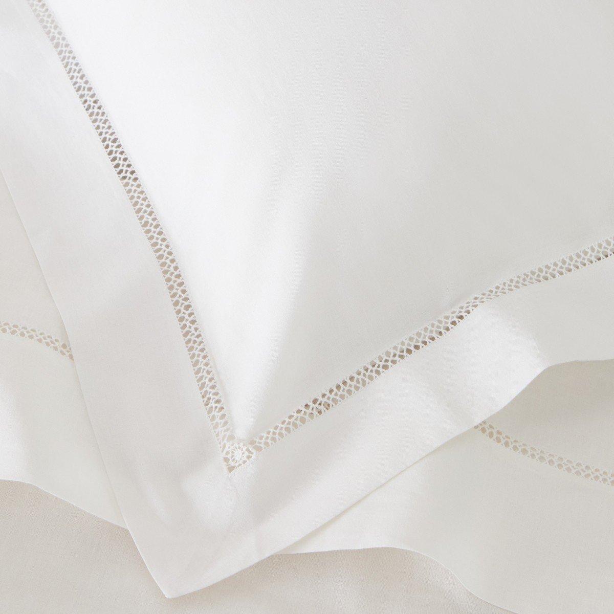 a close up of a white bed with white sheets and pillows