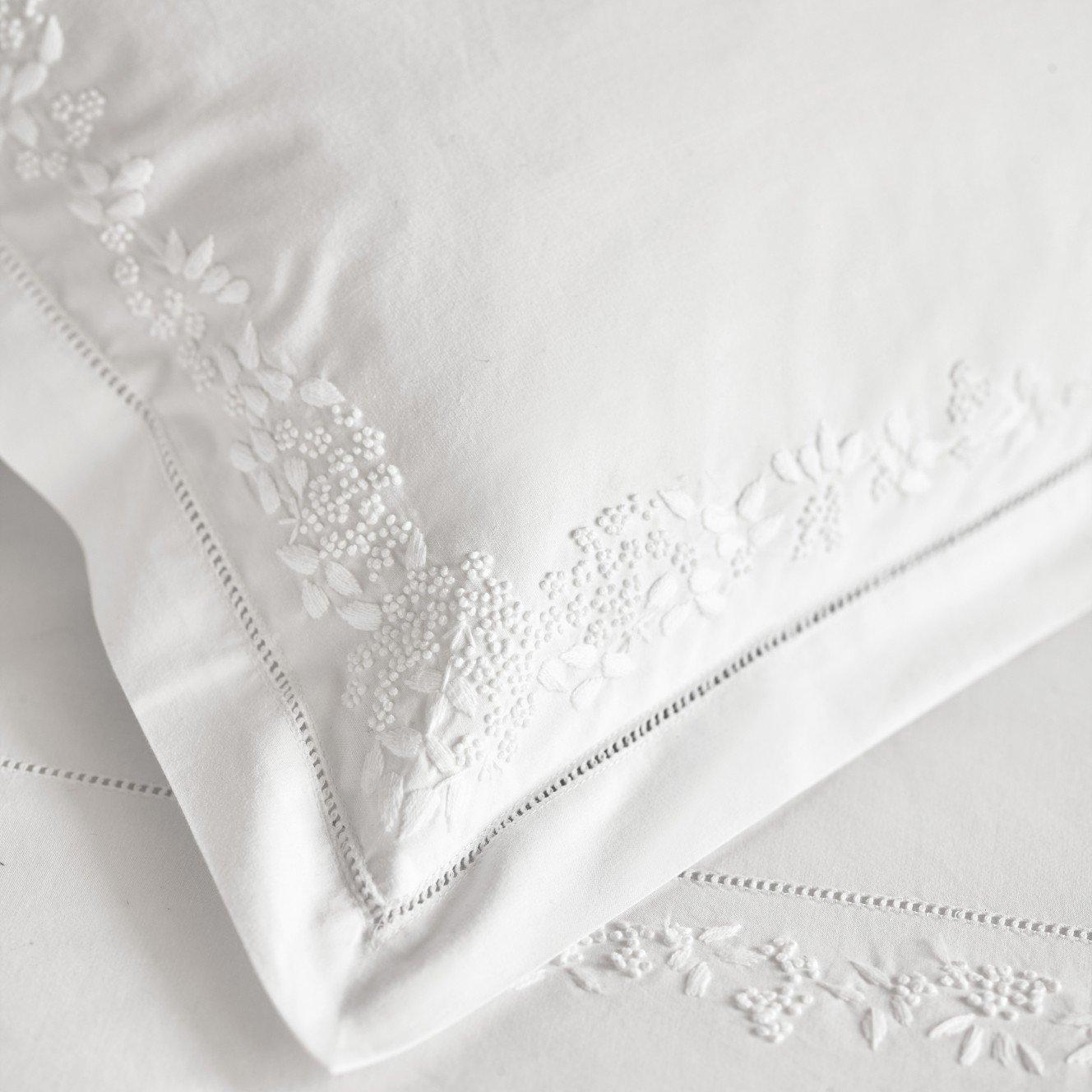 a close up of a white pillow with embroidered flowers on it