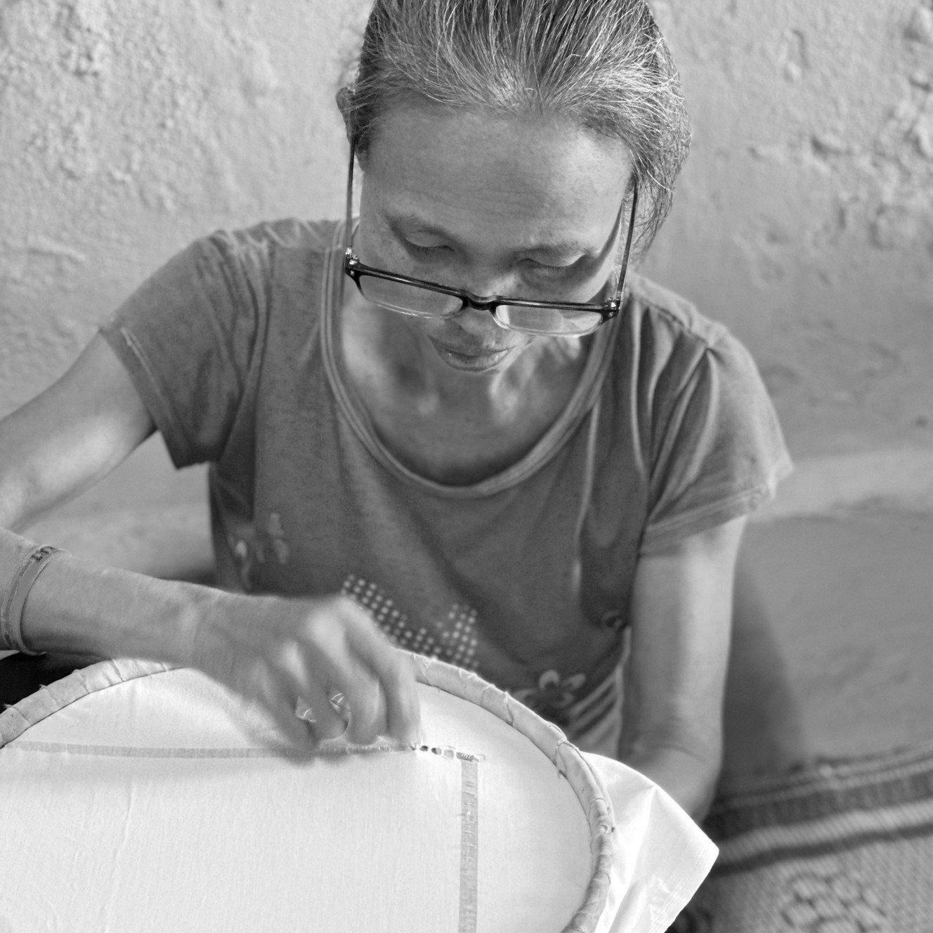 a woman in glasses working on a piece of fabric