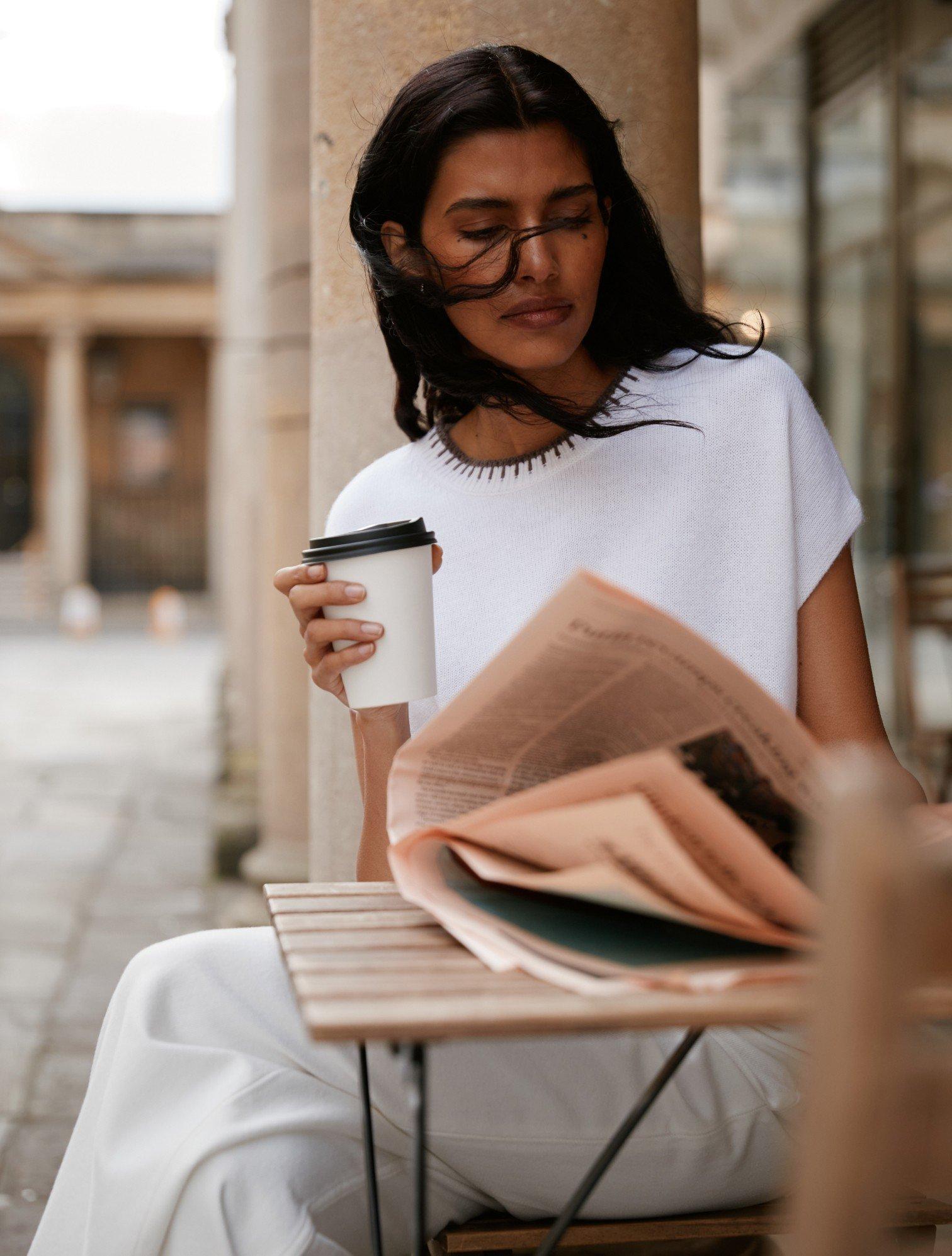 a woman sitting at a table with a cup of coffee