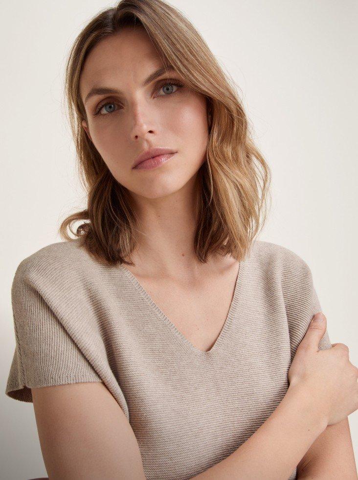 a woman with her arms crossed in a v neck sweater