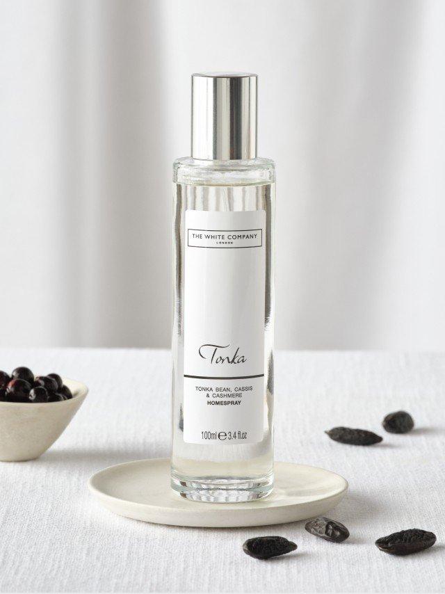 a bottle of perfume sits on a plate next to some blackberries