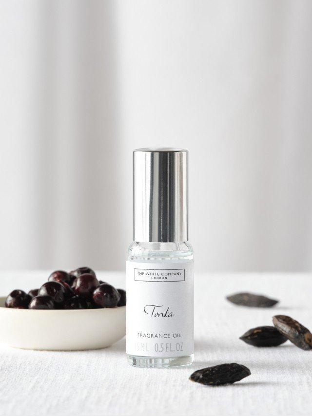 a bottle of oil next to a bowl of tonka beans