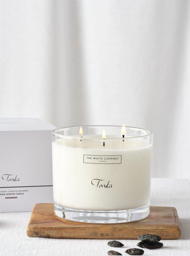 a candle sitting on a wooden tray next to some tonka beans