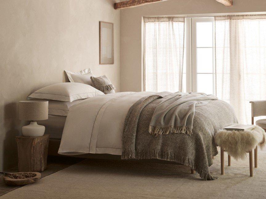 a bedroom with a bed, chair, and a large window