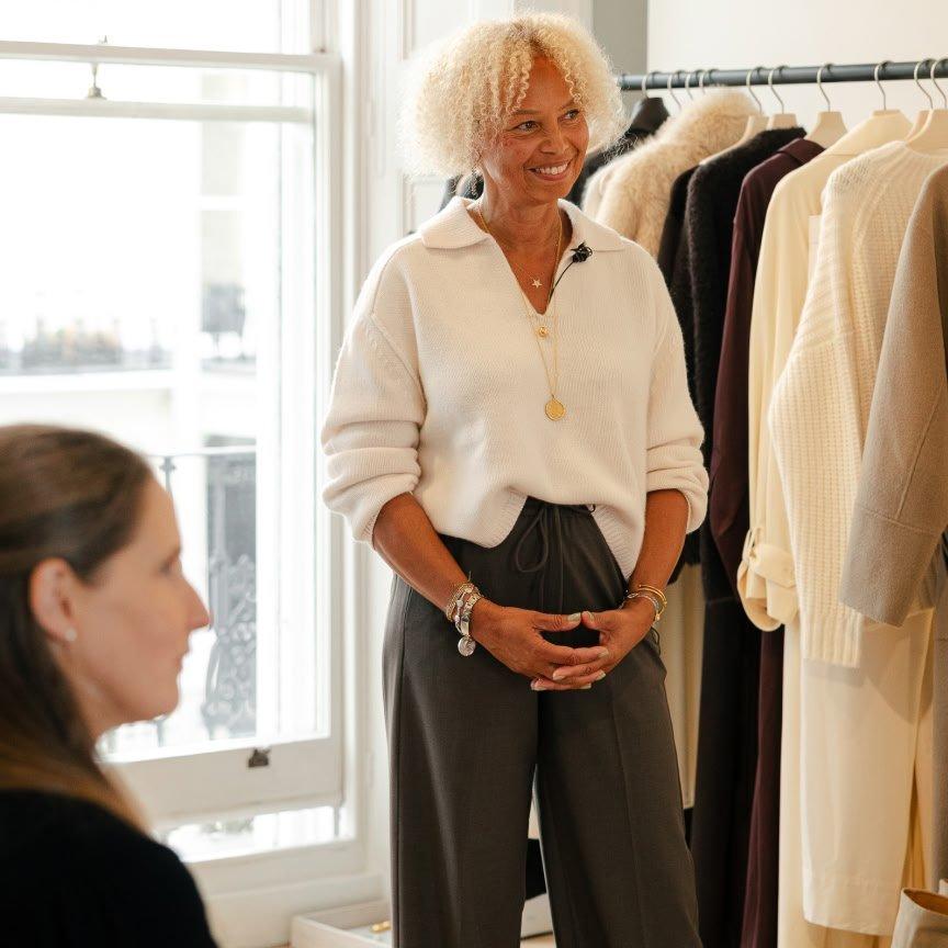 a woman is standing in front of a rack of clothes