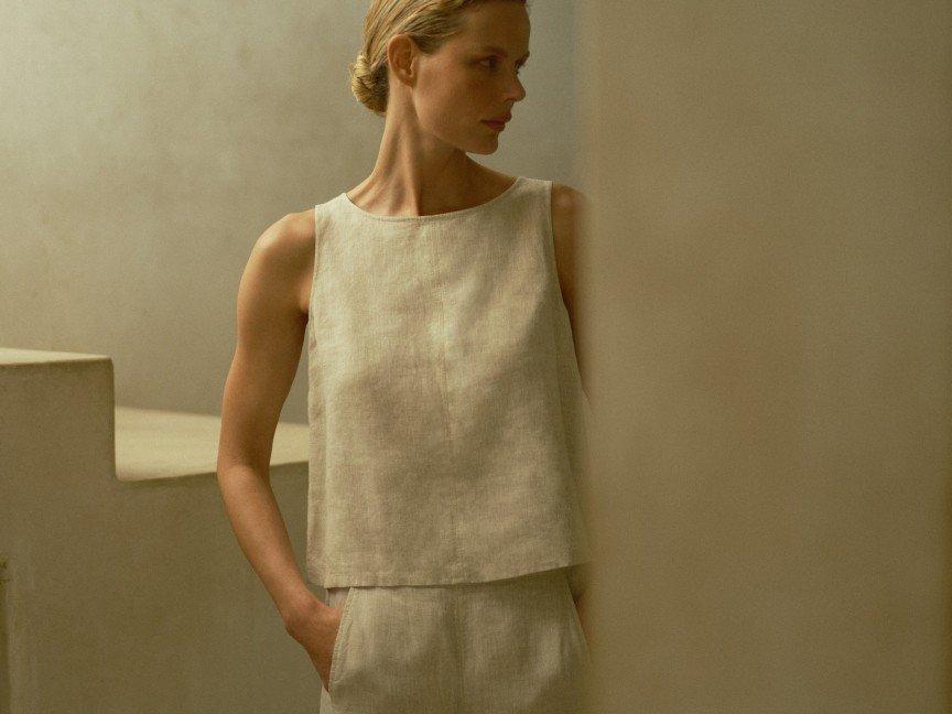 a woman in a white top and pants standing in a stairwell