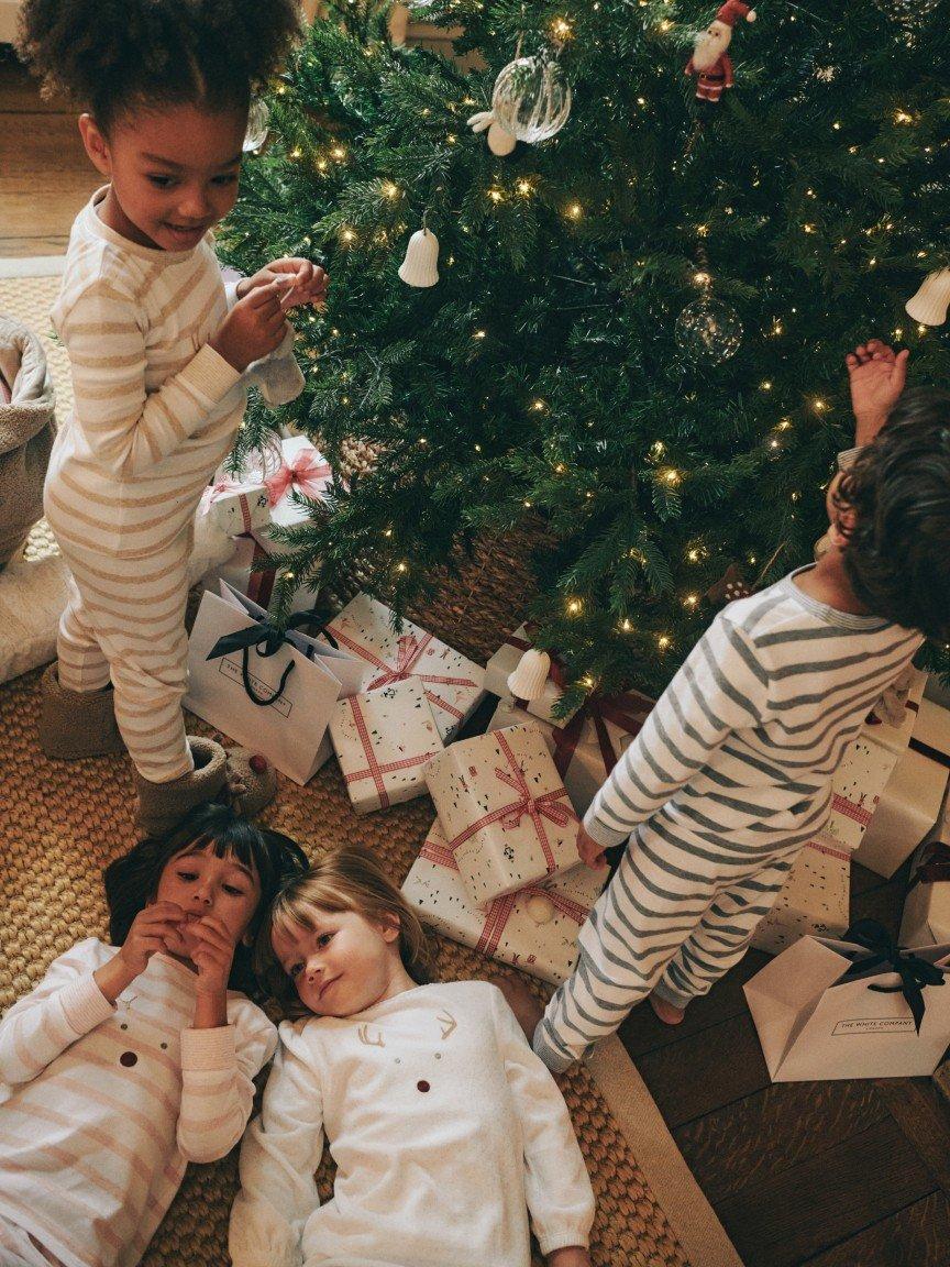 a group of children in pajamas around a christmas tree