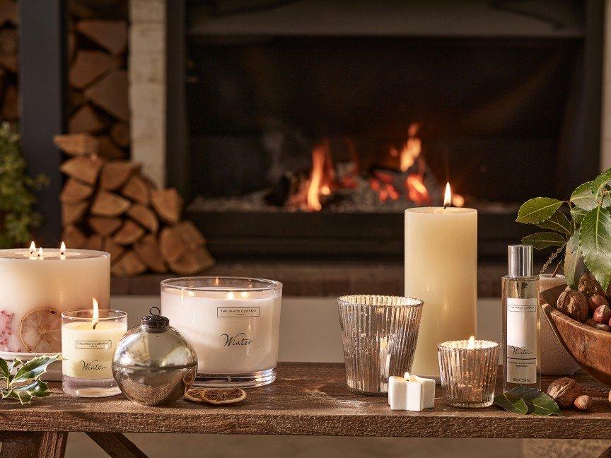 a table with candles and other items in front of a fireplace