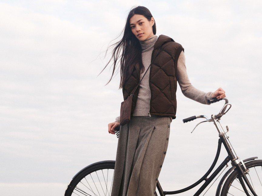 a woman standing next to a bike with a long skirt