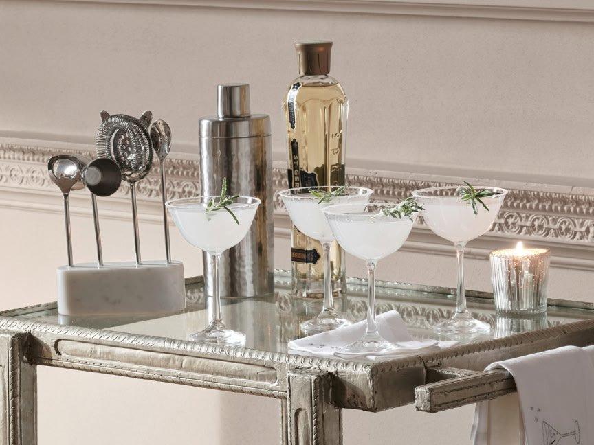 a glass table with four glasses and a bottle of liquor