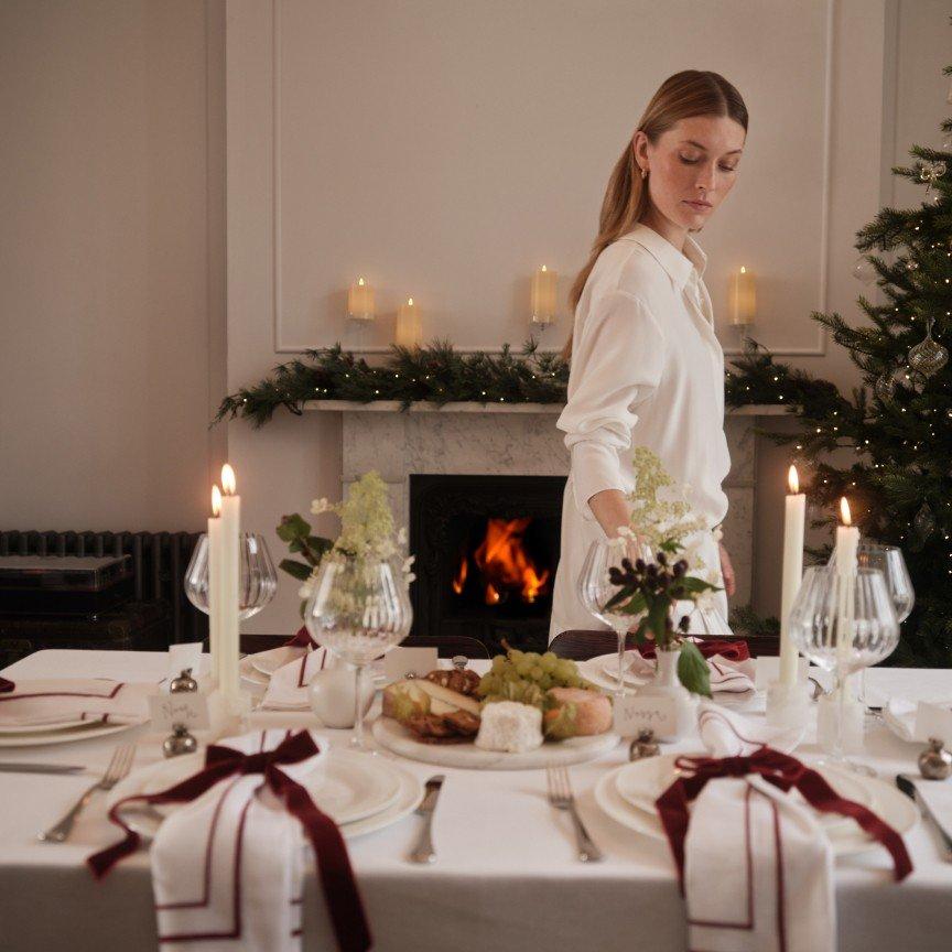 a woman setting a table for a christmas dinner in a living room