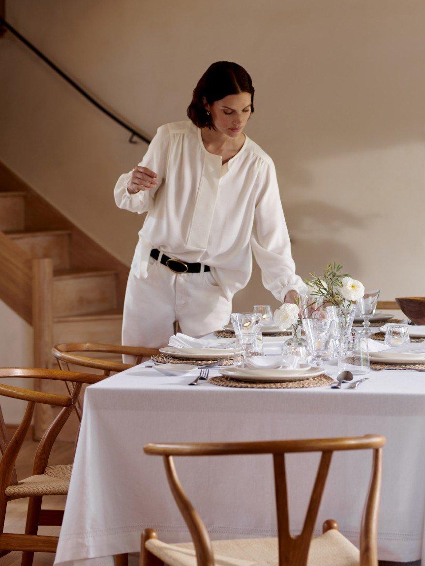 a woman standing at a table with a white table cloth