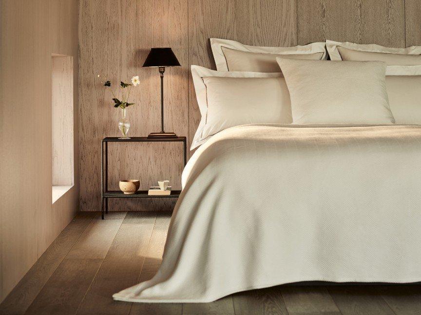 a bed with white sheets and pillows in a bedroom