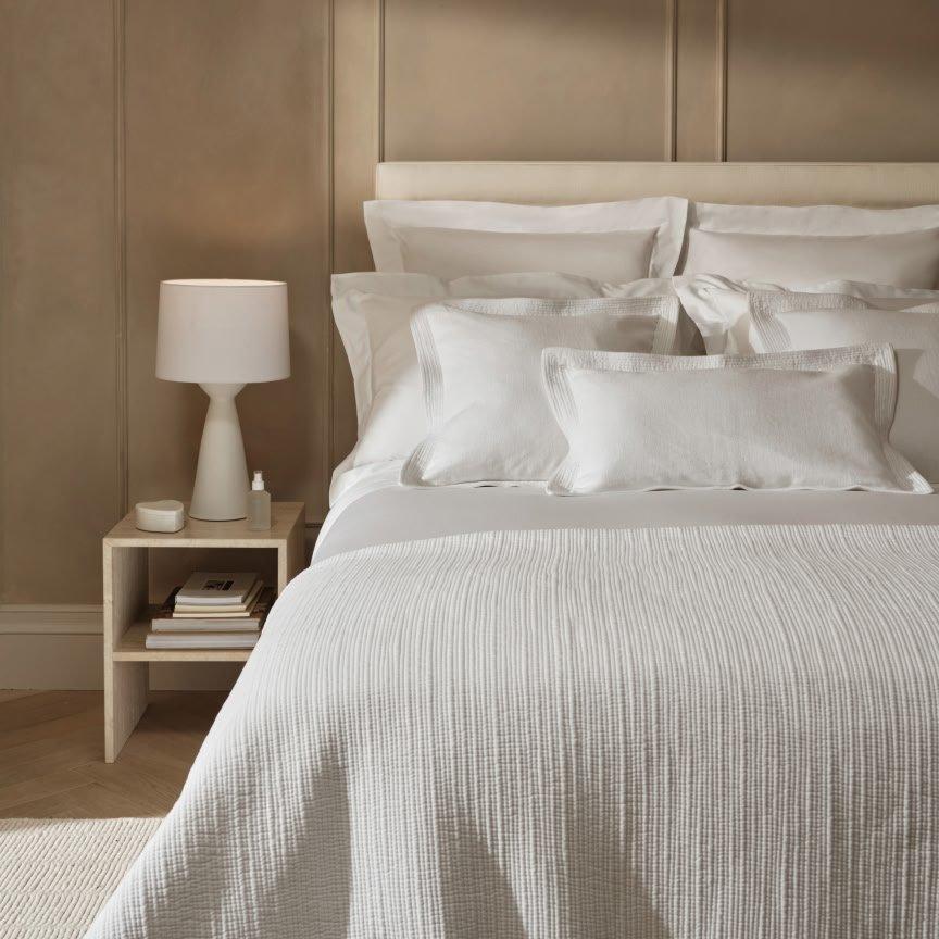 a bed with a white comforter and pillows on it