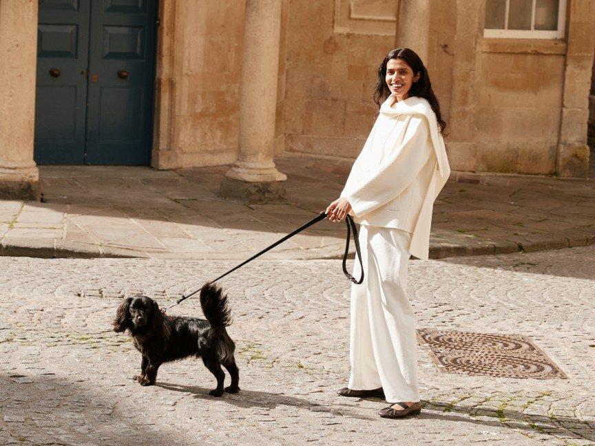 a woman in white standing on a street with a dog