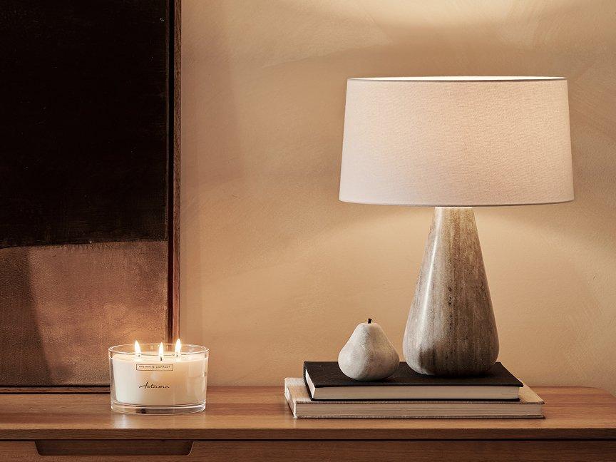 a candle and two pears sit on a table next to a lamp