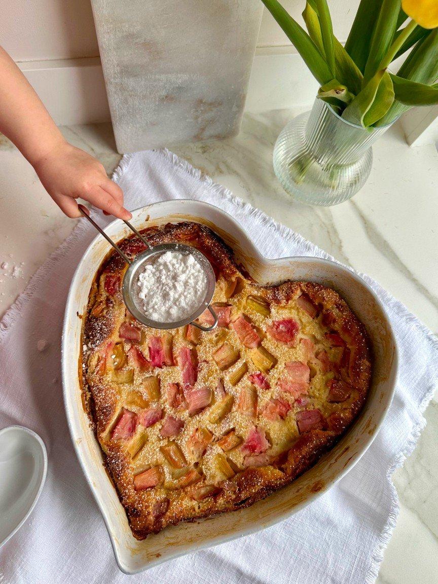 a person holding a spoon over a heart shaped dish of food