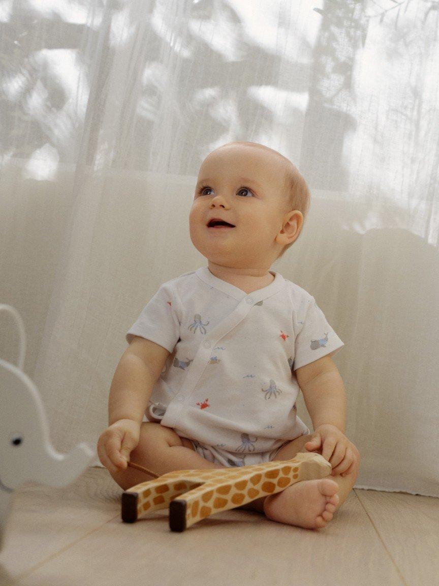 a baby sitting on the floor with a toy giraffe
