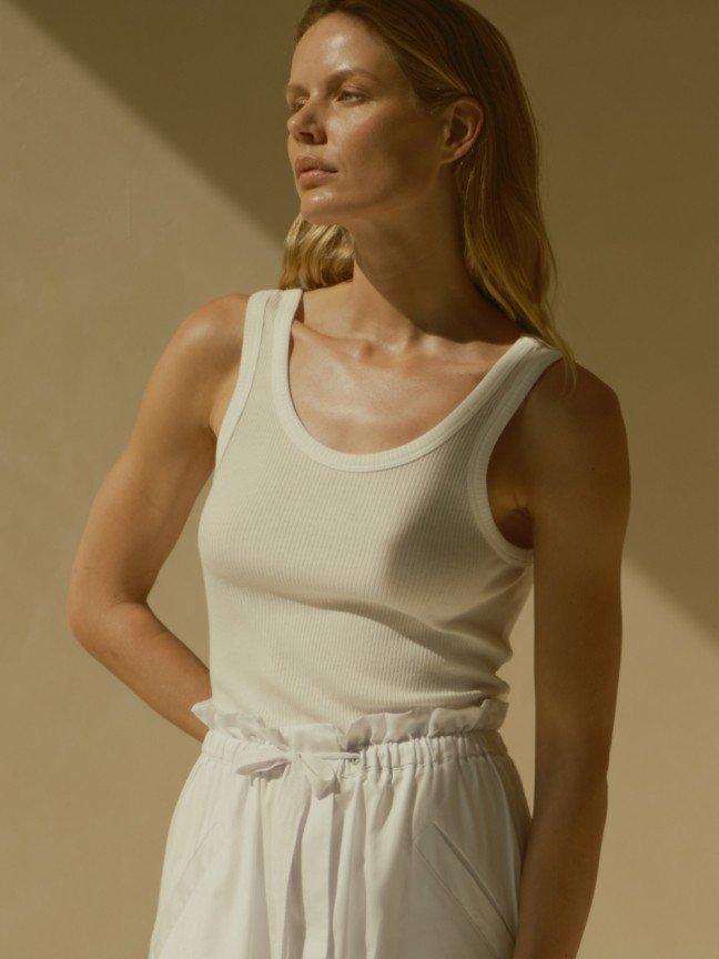 a woman in a white tank top and white skirt