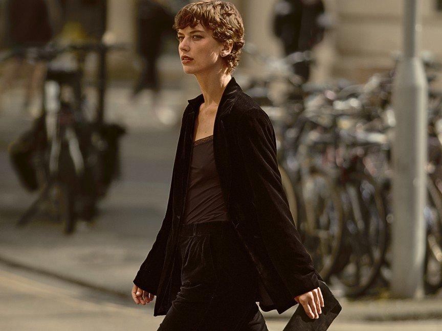 a woman in a black dress standing on a street