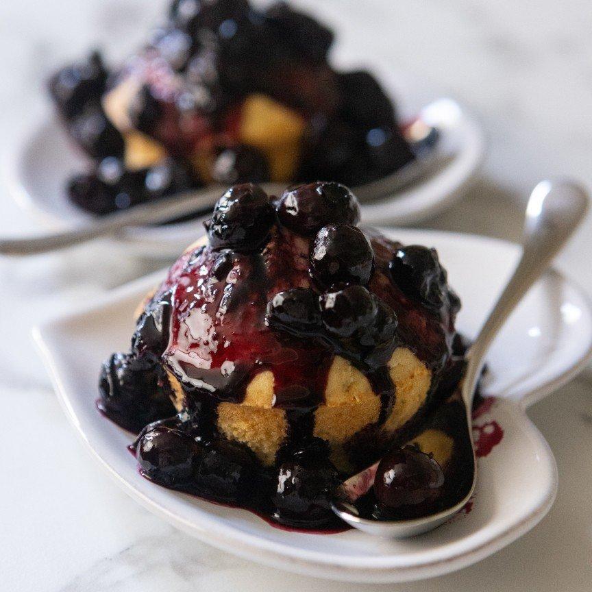 a close up of a dessert with blueberries and whipped cream