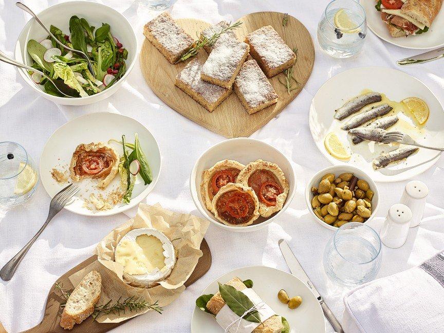 a table topped with plates of food and bowls of olives