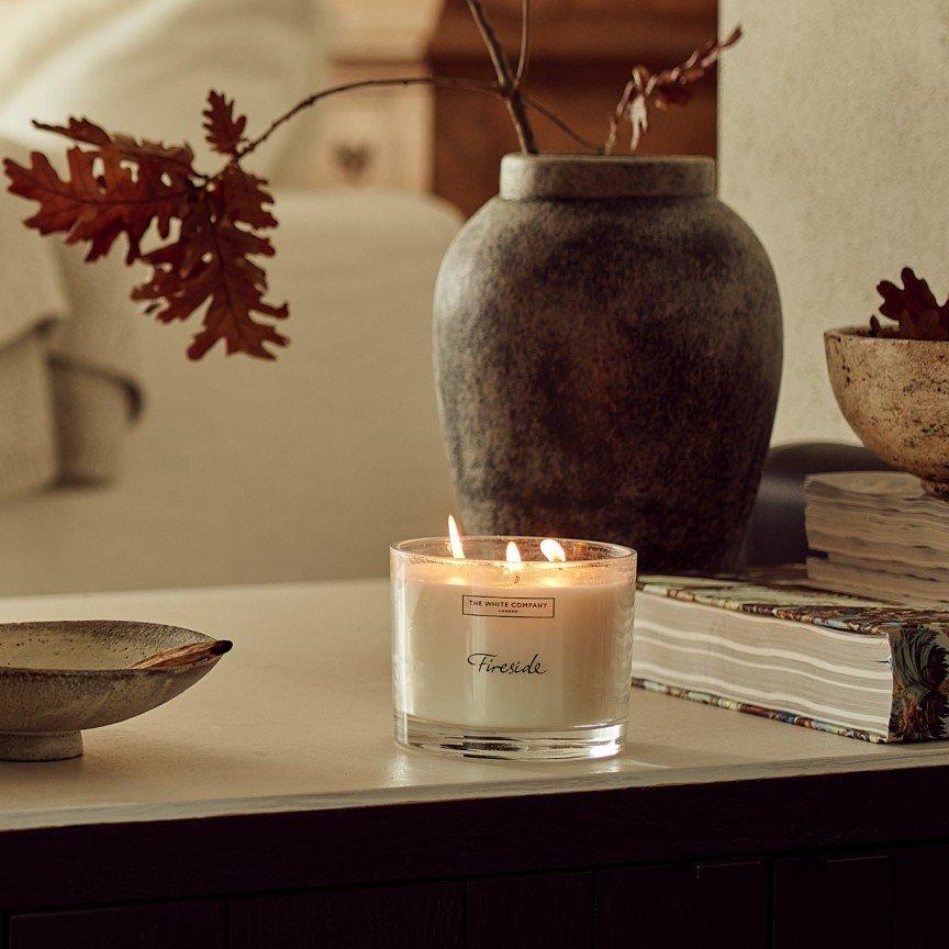 a candle on a table next to a bowl and a vase