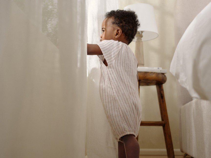 a small child standing in front of a window looking out