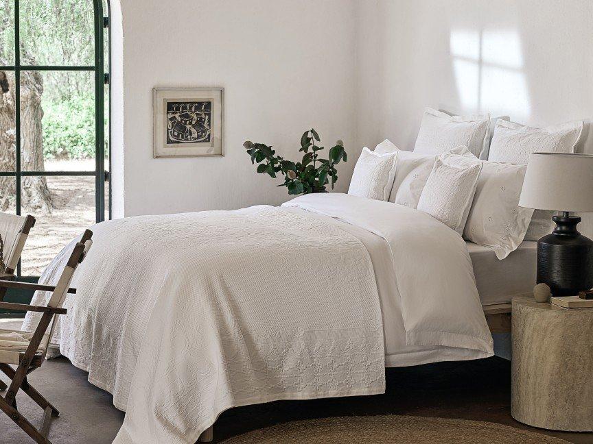 a bedroom with a bed, chair, and lamp in it