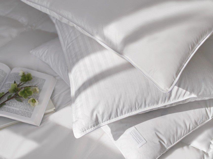 a pile of pillows on a bed with a book and a flower